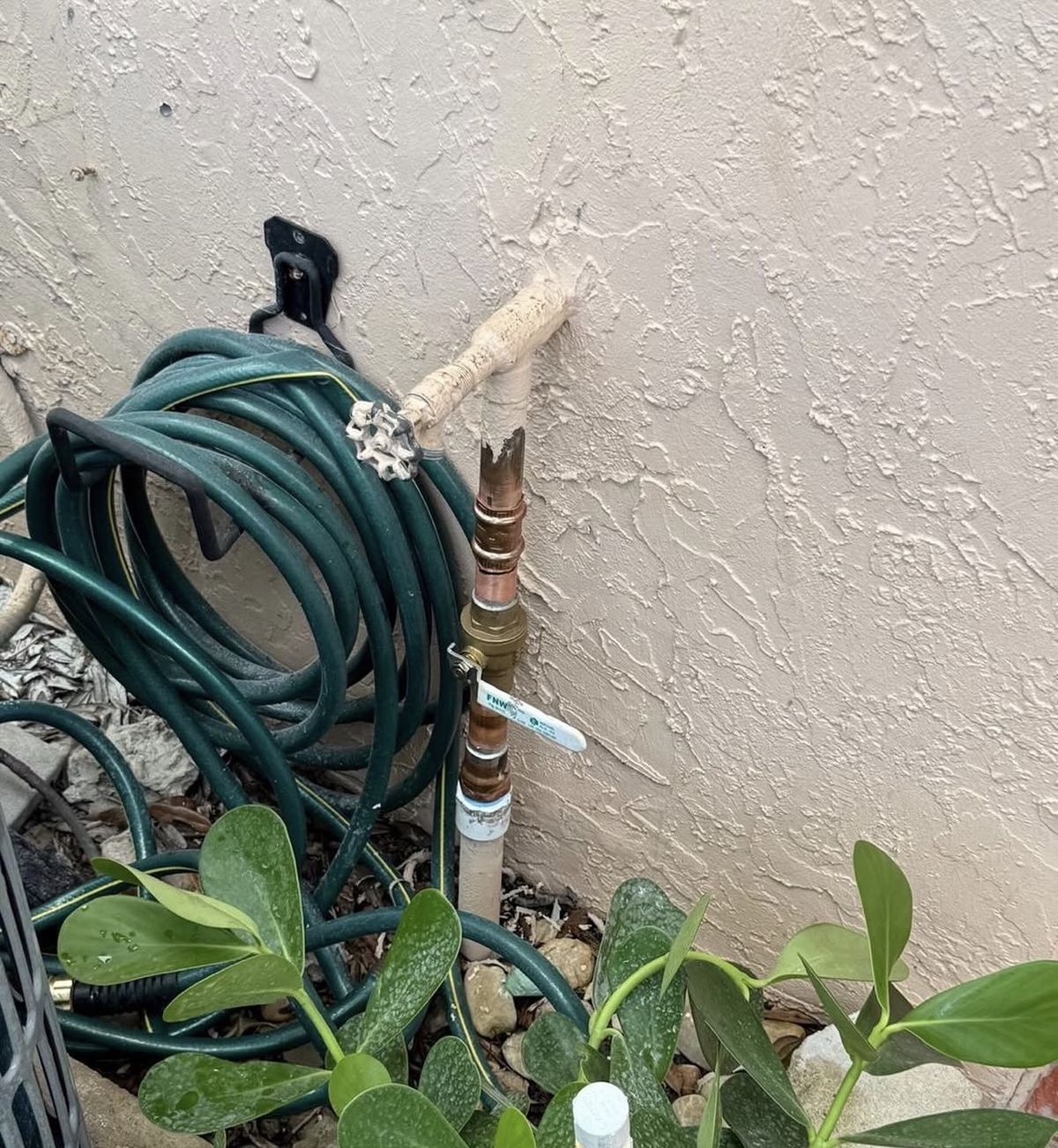 New brass ball valve and hose bib on a copper pipe along an exterior stucco wall